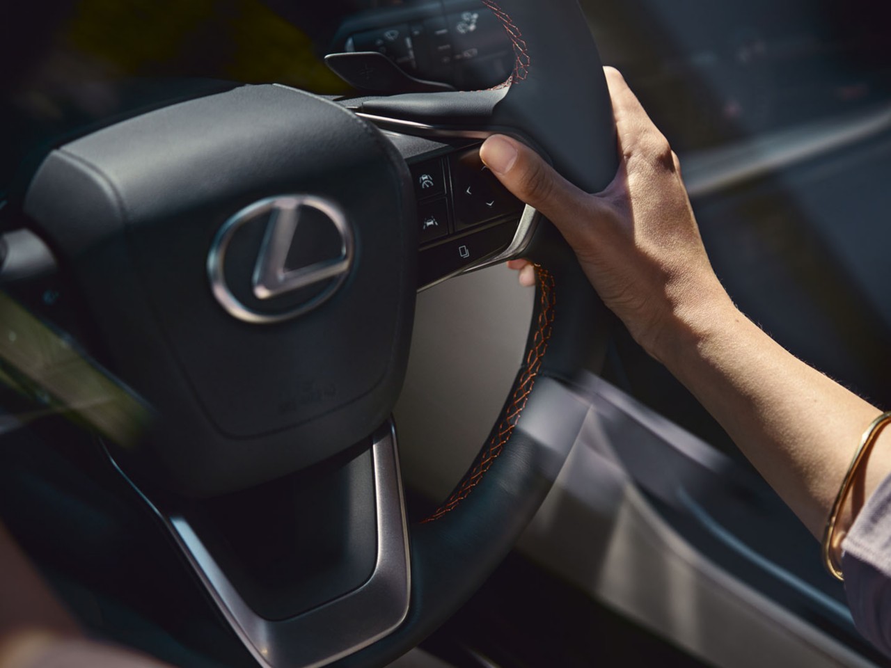 A hand on a Lexus steering wheel 